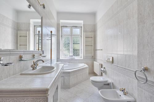 La salle de bains blanche est pourvue de 2 lavabos et de toilettes. dans l'établissement Villa Deluxe Apartments, à Karlovy Vary