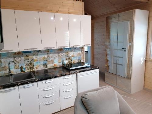 uma cozinha com armários brancos e um lavatório em Domek u Beaty em Rewal