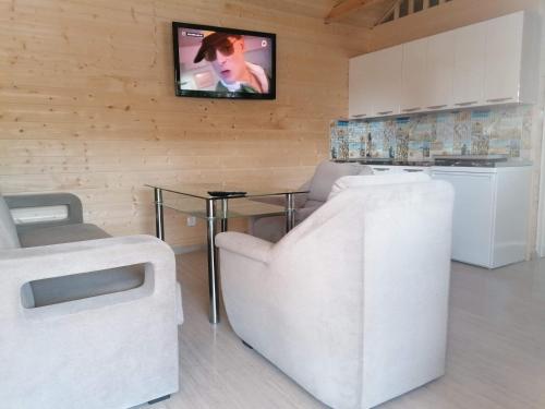 uma sala de estar com duas cadeiras brancas e uma televisão em Domek u Beaty em Rewal