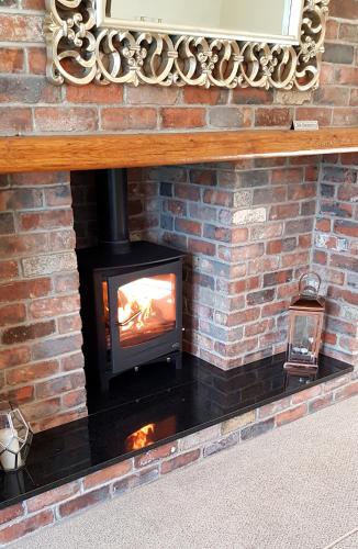 a fireplace with a stove in a brick wall at The Meadows B&B in Moville
