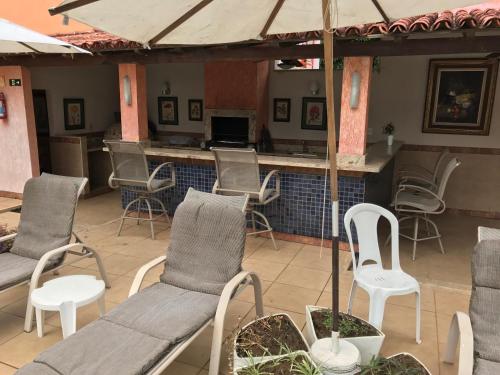 a patio with chairs and tables and a bar at Pousada Doce Vida Guarapari in Guarapari