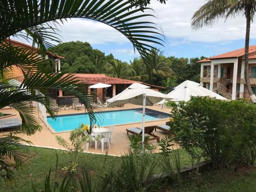 a resort with a swimming pool and umbrellas at Pousada Doce Vida Guarapari in Guarapari