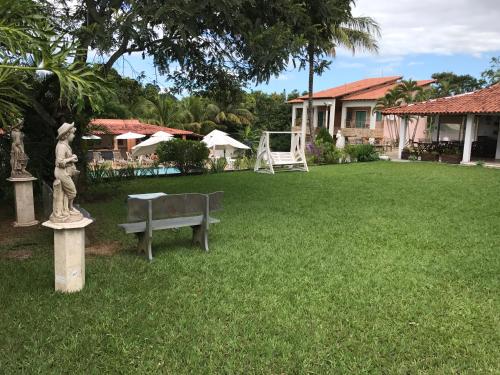 a garden with a bench in the yard of a house at Pousada Doce Vida Guarapari in Guarapari