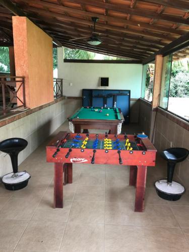 a ping pong table in a room with a pool at Pousada Doce Vida Guarapari in Guarapari