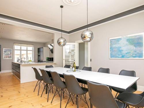 12 person holiday home in Nyborg في نيوبورغ: غرفة طعام ومطبخ مع طاولة وكراسي بيضاء