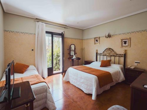 a bedroom with two beds and a tv and a window at Hotel Doña Carmen in Tordesillas