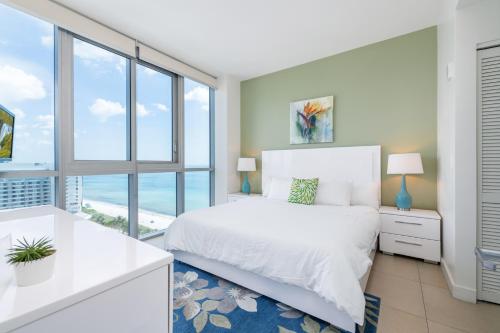 a bedroom with a white bed and a large window at Global Luxury Suites at Monte Carlo in Miami Beach