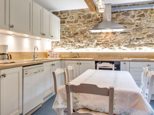 eine Küche mit einem Tisch, Stühlen und einer Steinmauer in der Unterkunft Enticing Holiday Home in Viroinval near Forest in Le Mesnil
