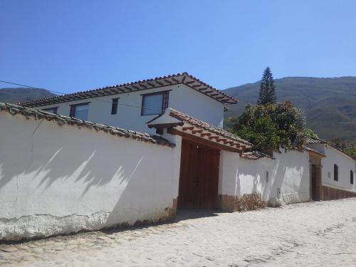 a white building with a door and a fence at Posada Portal de la Villa in Villa de Leyva