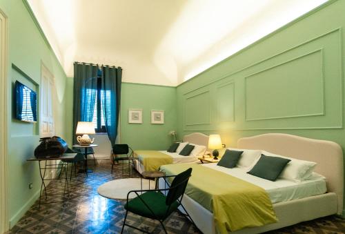 Habitación de hotel con 2 camas y sillas en I PRINCIPI di CASADOR HOUSE HOTEL, en Milazzo