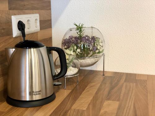 un bollitore per il tè seduto su un tavolo con una ciotola di fiori di City Apartments, Outlet 100 Meter a Metzingen