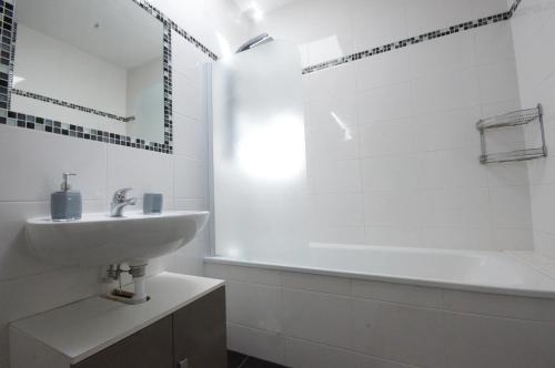 biała łazienka z umywalką i wanną w obiekcie F2 Aux pieds des Thermes 3 étoiles w mieście Luxeuil-les-Bains