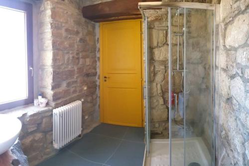 a bathroom with a shower with a yellow door at Casa nella Roccia in Castelmezzano
