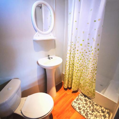 a bathroom with a toilet and a sink and a mirror at Casa Caravanas in Paracas