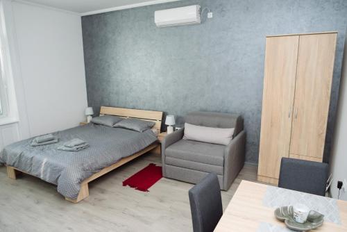 un dormitorio con una cama y una silla en D&D apartments, en Subotica