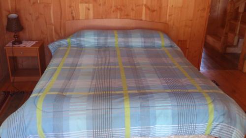 a bed with a blue and yellow comforter in a room at Cabañas Los Canelos Pucon, Hermosa Granja de 20 hectaréas a orillas del Río Liucura in Pucón
