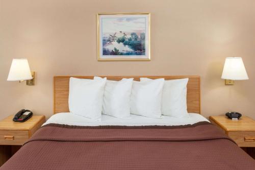 a hotel room with a bed with white pillows at Days Inn by Wyndham Charleston in Charleston