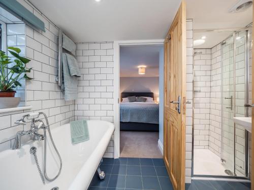a bathroom with a bath tub and a bedroom at Horatio’s in Worstead