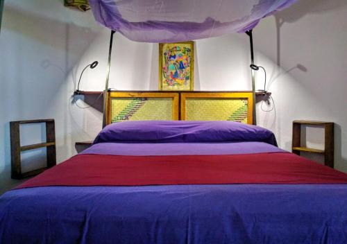 a bedroom with a bed with purple sheets and a canopy at Posada Olivo in Mazunte