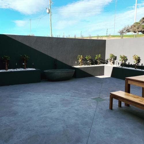 a patio with a bench and a wall with plants at The Cove Tasmania in Devonport