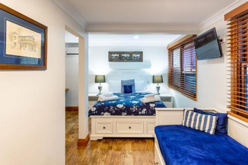 a bedroom with a blue bed and a tv at The Village B&B in Gold Coast