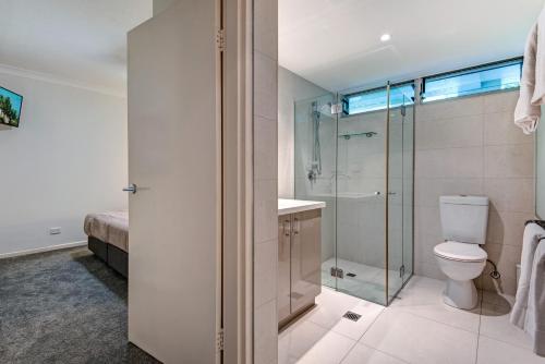 a bathroom with a toilet and a glass shower at Poinciana Lodge - 2 bedroom - on Hamilton Island by HIHA in Hamilton Island
