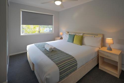 a bedroom with a large white bed with a window at Ingenia Holidays One Mile Beach in One Mile