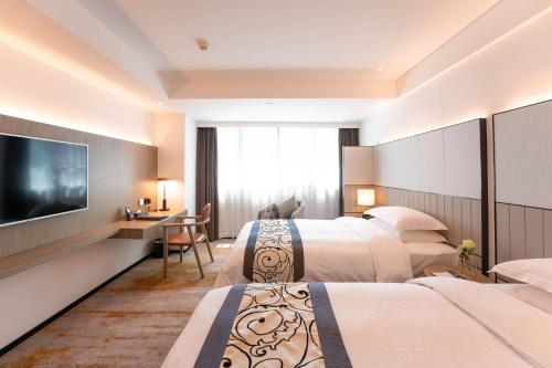 a hotel room with two beds and a flat screen tv at Zhong Tai Lai Hotel Shenzhen in Shenzhen