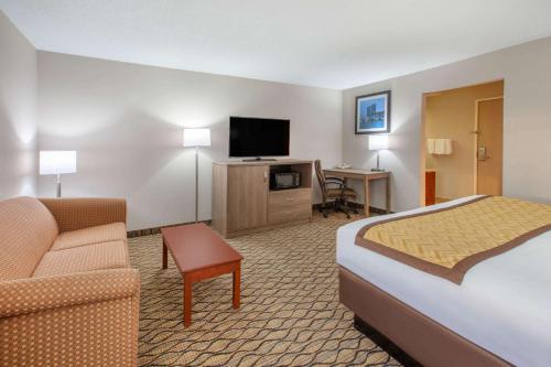 a hotel room with a bed and a couch and a television at Baymont by Wyndham Grand Rapids Airport in Grand Rapids