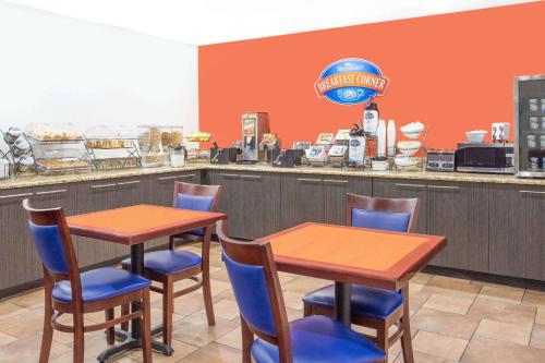 a restaurant with two tables and chairs in front of a counter at Baymont by Wyndham Green Bay in Green Bay