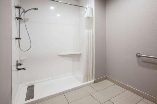 a white bathroom with a shower and a tub at Baymont by Wyndham Traverse City in Traverse City