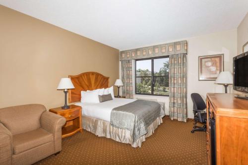 a hotel room with a bed and a chair and a television at Baymont by Wyndham Asheville/Biltmore in Asheville