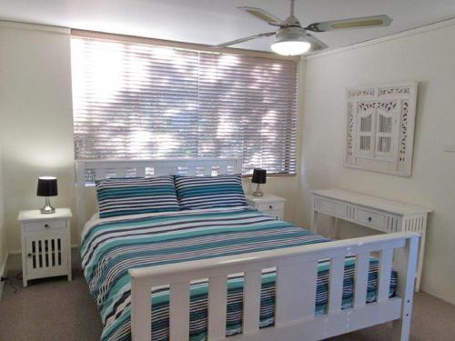 a bedroom with a white bed and a window at Harbourside 13 fantastic waterfront unit in Soldiers Point