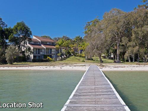 a wooden dock in the water in front of a house at Harbourside 13 fantastic waterfront unit in Soldiers Point