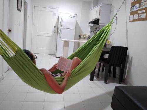 a child laying in a hammock with a book at Rodadero Parador, apartamentos a 20 metros de la playa in Santa Marta