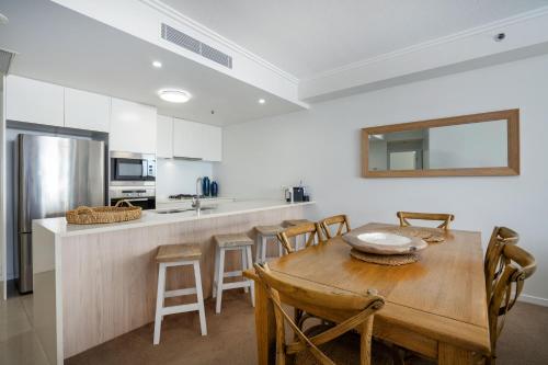a kitchen and dining room with a wooden table and chairs at Reflections Tower Two in Gold Coast