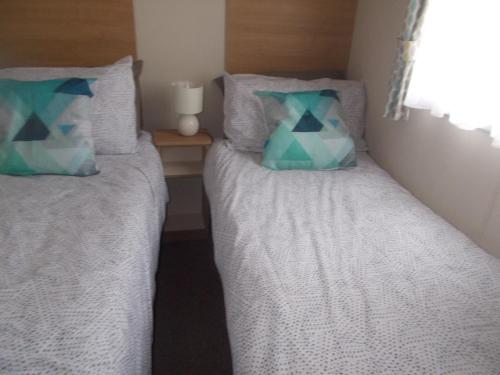 two beds in a bedroom with two pillows at ty gwyn in Abergele