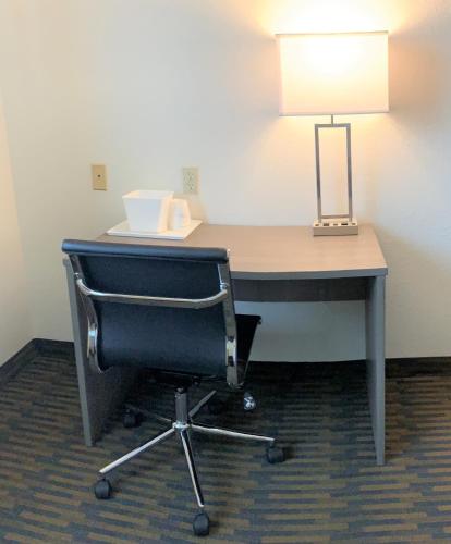 a desk with a chair and a lamp on it at Baymont by Wyndham Paw Paw in Paw Paw