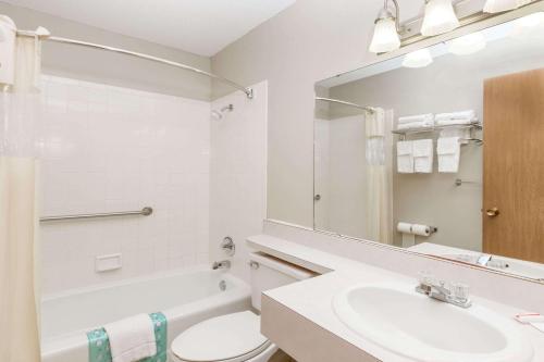 a bathroom with a sink and a toilet and a mirror at Days Inn & Suites by Wyndham Des Moines Airport in Des Moines