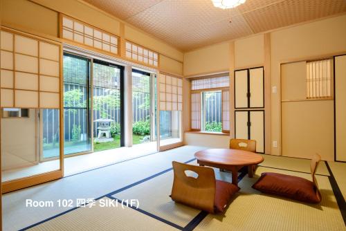 een kamer met een tafel, stoelen en ramen bij Luck You Kyoto in Kyoto