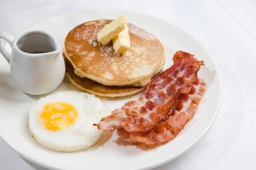 a plate with eggs bacon and pancakes and a cup of coffee at Bay Area Suites Manila in Manila