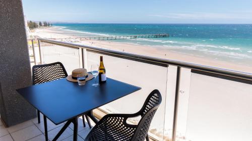 
a table and chairs at a beach with a view of the ocean at Oaks Glenelg Plaza Pier Suites in Adelaide
