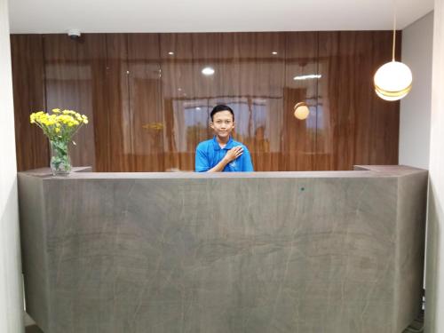 a man is standing behind a reception counter at Hotel Youstay Semarang by Sinergi in Kalibanteng-lor