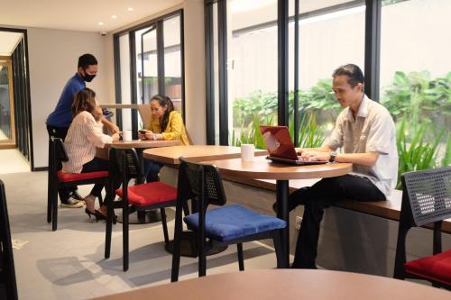 a group of people sitting at tables with a laptop at Hotel Youstay Semarang by Sinergi in Kalibanteng-lor