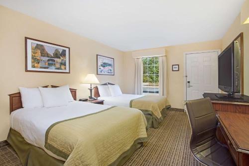 een hotelkamer met 2 bedden en een flatscreen-tv bij Baymont by Wyndham Forest City in Forest City