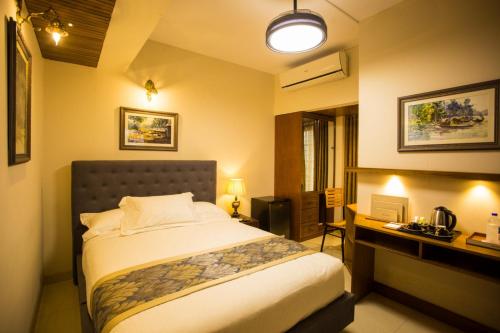 a bedroom with a bed and a desk and a bed sidx sidx sidx at Shinepukur Suites in Dhaka
