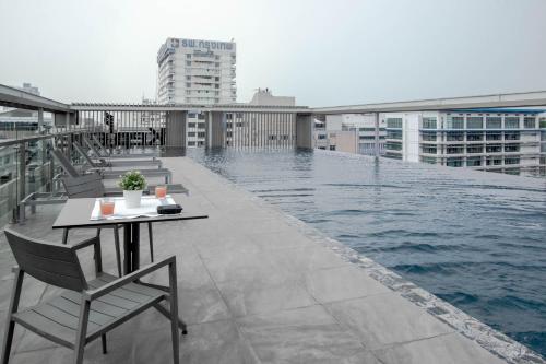 a balcony with a table and chairs next to a pool at Kepler Residence Bangkok in Bangkok