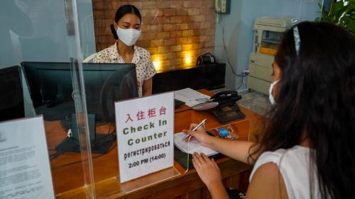 a woman wearing a face mask standing in front of a counter at Sugar Palm Grand Hillside - SHA Plus in Kata Beach