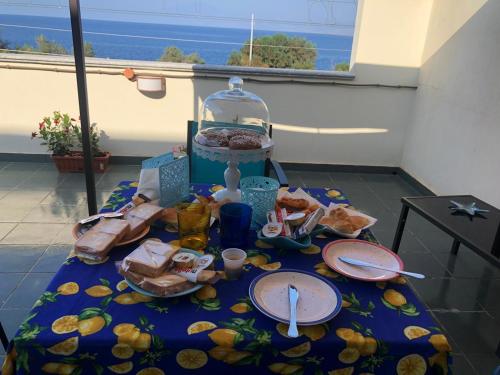 a table with food and plates on it with a view of the ocean at Il corallo azzurro in Reggio Calabria