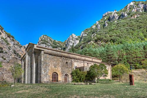 an old stone church with mountains in the background at Hotel Boutique Bodegas De Arnes - Adults Only in Graus